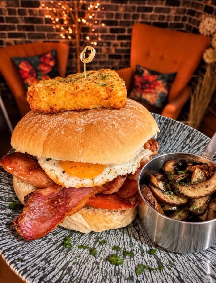 Stacked burger with a fried egg and a bowl of mushrooms