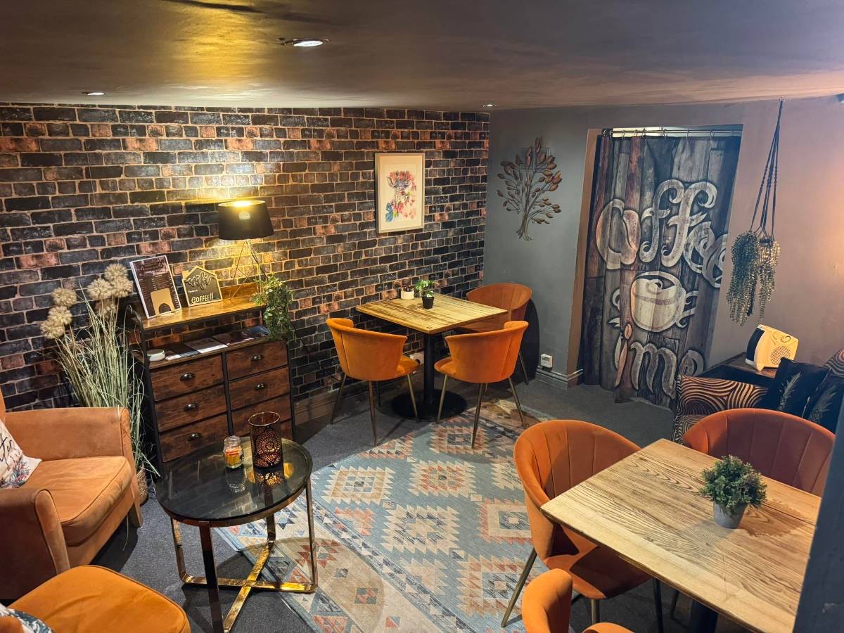 The downstairs room with orange velvet chairs, rugs and exposed brick